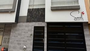 A modern multi-story building with a white facade, stone accents, and black garage doors. - Apartment for 8 guests in the center of Pasto 3 bedrooms 2 bathrooms (Pasto)