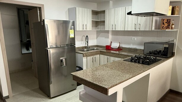 A modern kitchen with a stainless steel refrigerator, a built-in gas stove, and white cabinetry. - Apartment for 8 guests in the center of Pasto 3 bedrooms 2 bathrooms (Pasto)