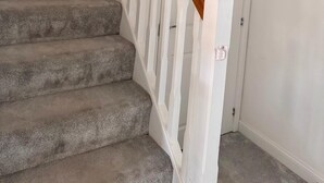 A staircase with carpeted steps and wooden handrails, leading to a white door. - Grand 4-bed House in Ebbsfleet Valley, Garden & Parking Space (Swanscombe)