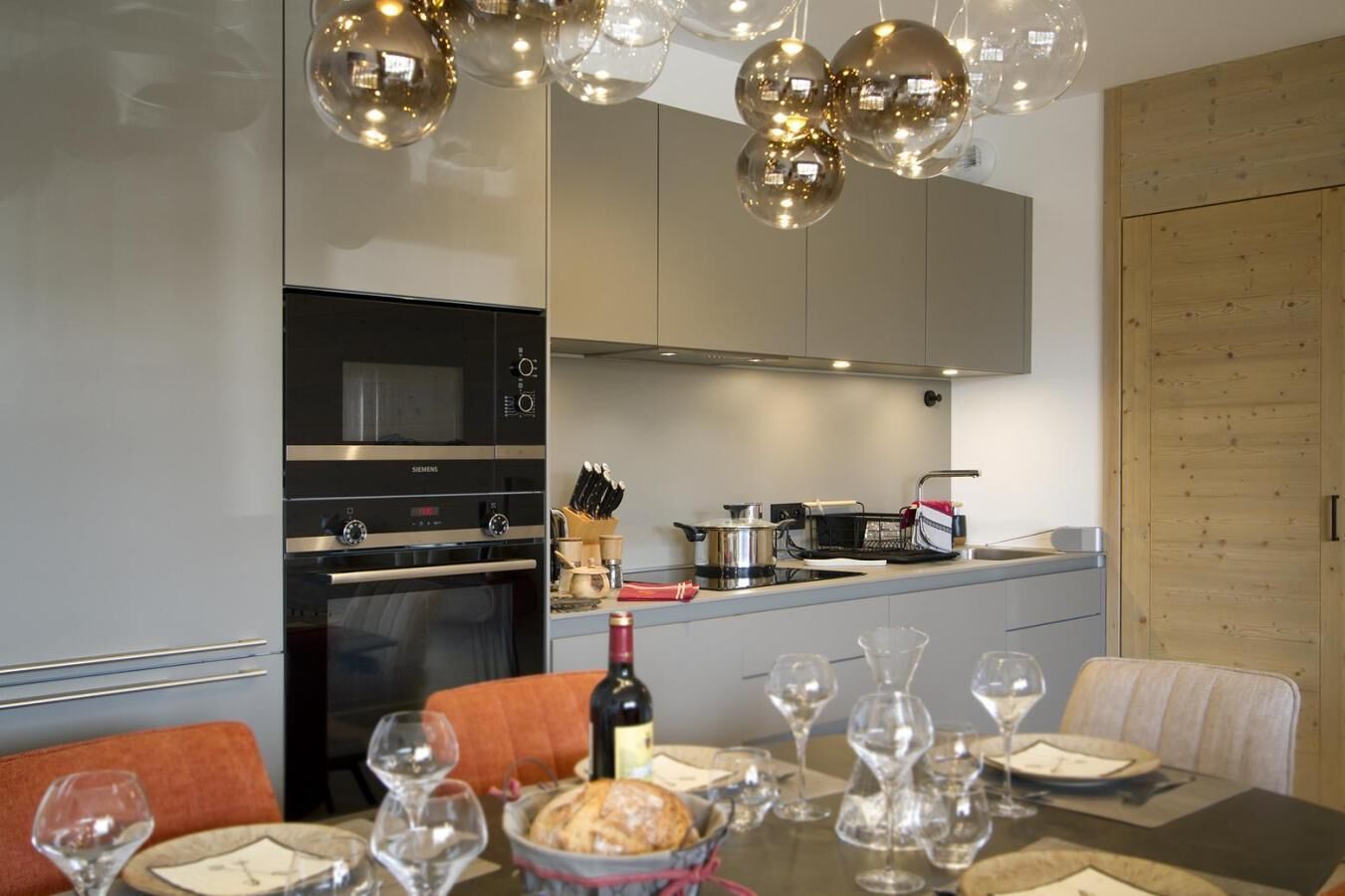 Une cuisine moderne équipée d’un four encastré, d’un micro-ondes et d’un coin repas avec une table mise pour le repas.