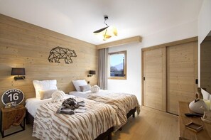 Quarto de hotel moderno com parede de madeira, cama com manta estampada, janela com vista e placa indicando o número do quarto.