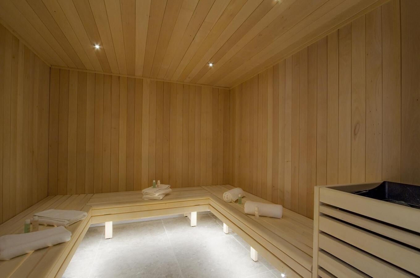 Een sauna met houten wanden en banken, een bank met handdoeken en een bank met een zwart dienblad.