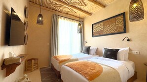Habitación de hotel con dos camas, un ventanal grande con cortinas, techo de madera y una obra de arte colgada en la pared.