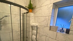 Kylpyhuone, jossa on lasiseinällä varustettu suihku, wc ja pesuallas.