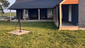 A house with a dark roof, a porch, and a grassy yard. - Historic Farm Stay at The Hager Hideaway (Harrodsburg)