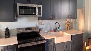 A modern kitchen with dark cabinets, a stainless steel microwave, an oven, and a sink. - Historic Farm Stay at The Hager Hideaway (Harrodsburg)