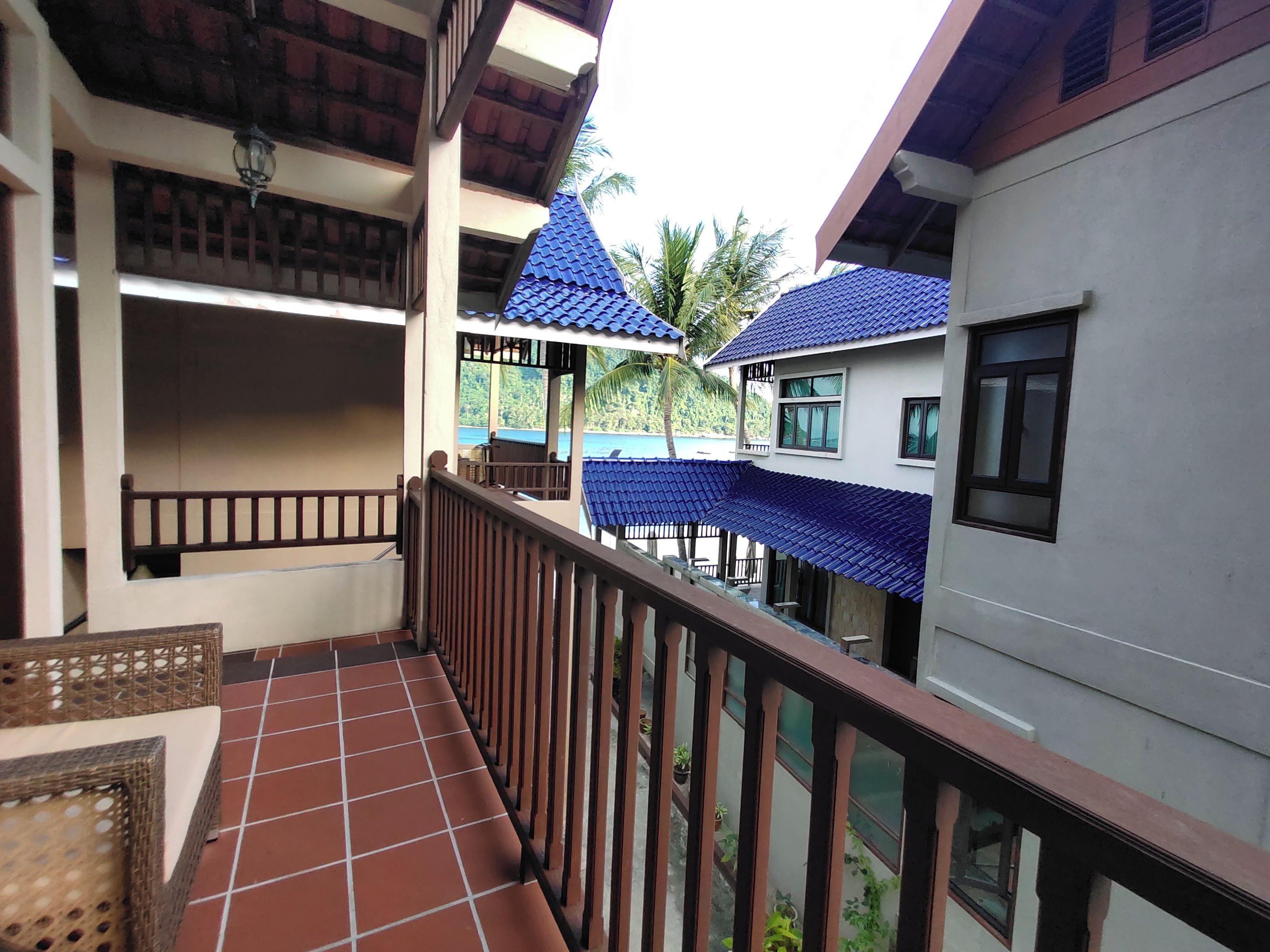 A multi-level building with balconies, a tiled floor, and a view of the sea.
