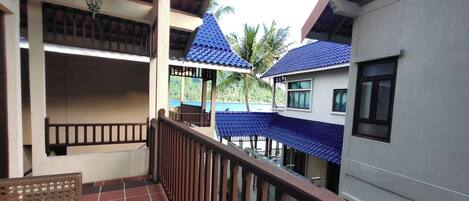 A multi-level building with balconies, a tiled floor, and a view of the sea.