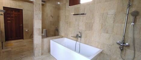 A modern bathroom with a large bathtub, a shower, and a marble floor.