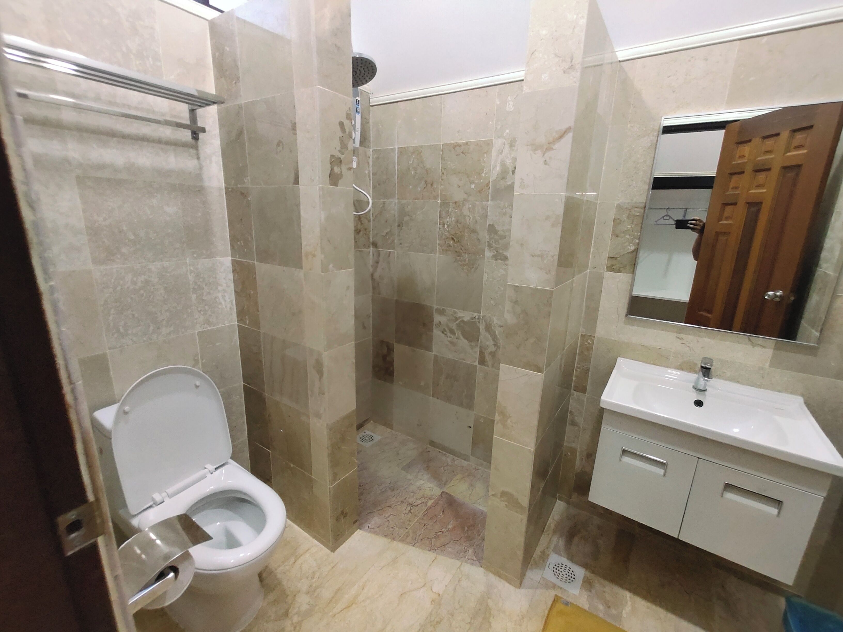 Un baño con inodoro, ducha, lavamanos y espejo.