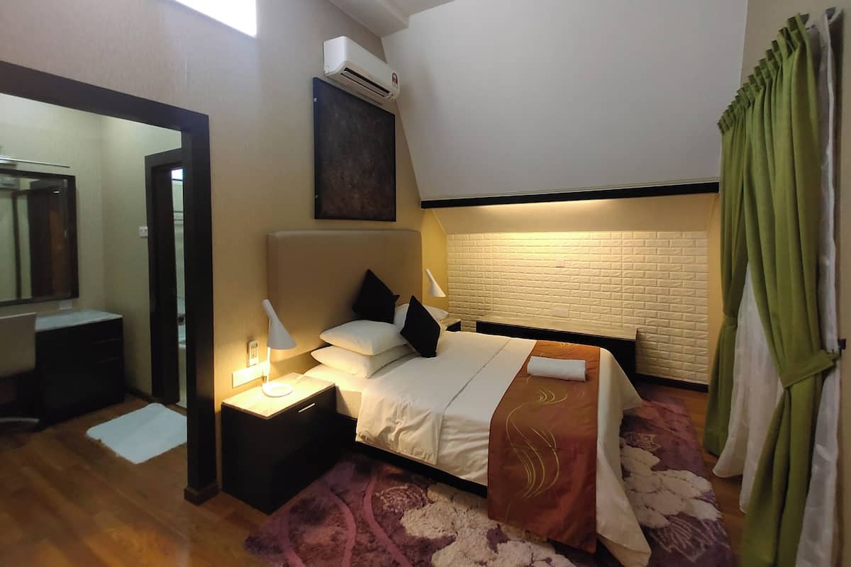 A bedroom with a bed, bedside table, lamp, and a wall-mounted air conditioner.