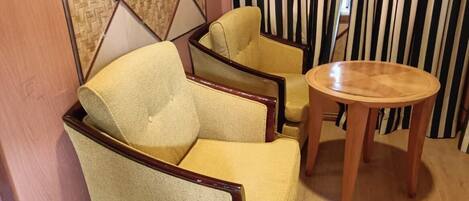 A corner of a room with two yellow armchairs and a small wooden table.