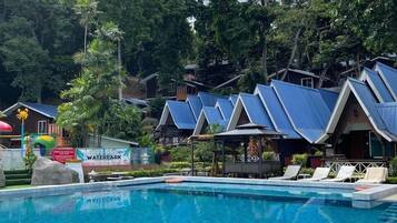 A swimming pool with blue-tiled edges, surrounded by trees and a sign reading "Kids Mini Waterpark".
