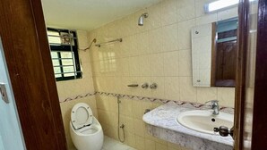 Un baño con inodoro, lavamanos, ducha y espejo.