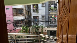 Vista desde un balcón con barandilla metálica, sobre una calle con motocicletas y bicicletas estacionadas, y edificios al fondo.