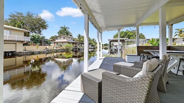 A covered outdoor area with wicker furniture and a view of a water body. - Lake Okeechobee Fishing Retreat (Okeechobee)