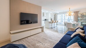 Ein modernes Wohnzimmer mit Flachbildfernseher, einer Couch und einer Pendelleuchte.