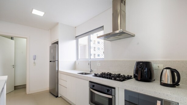 A modern kitchen with a stainless steel refrigerator, a gas stove, an oven, and a microwave. - Apto 3 quartos alto padrão em BC - GTR0301 (Balneário Camboriú)