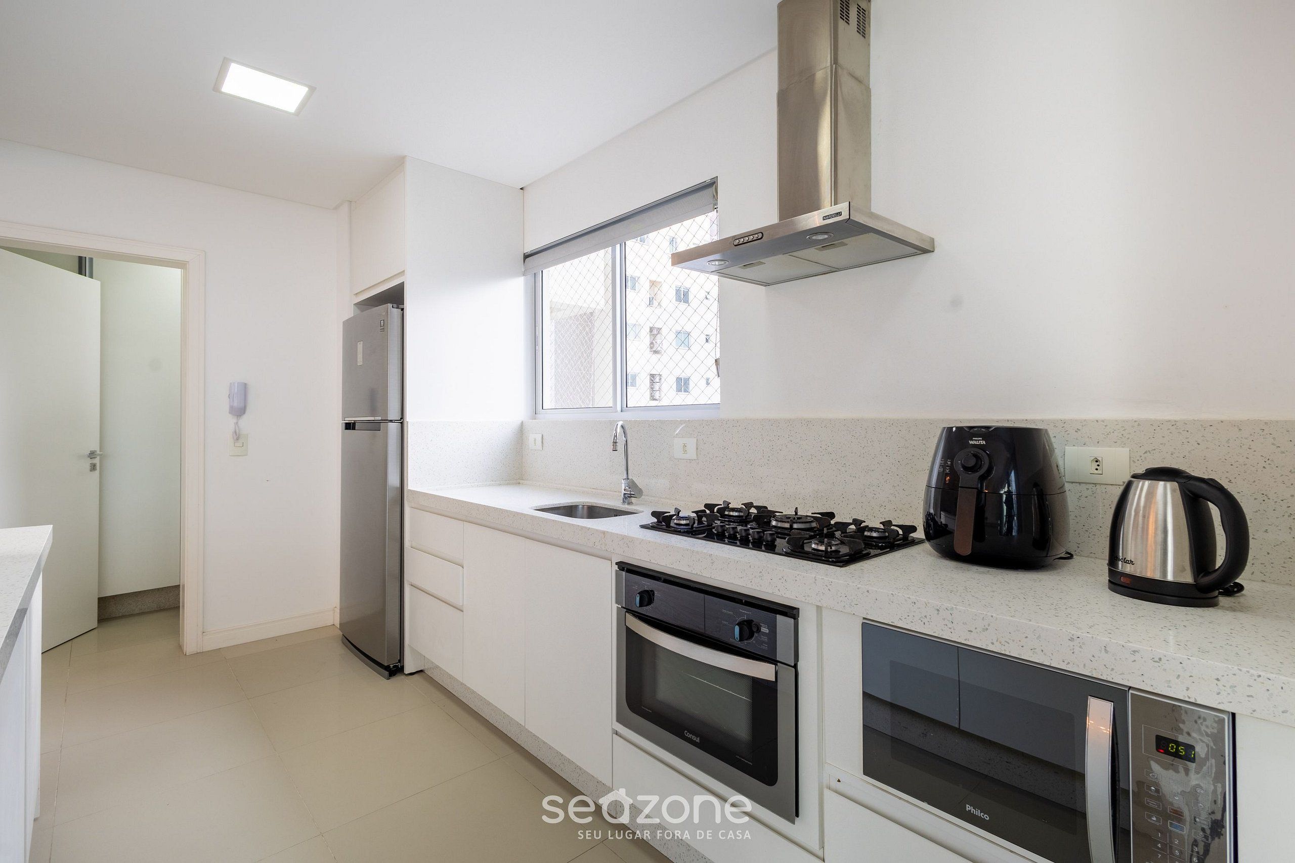 Una cocina moderna con un refrigerador de acero inoxidable, una estufa a gas, un horno y un microondas.