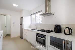 A modern kitchen with a stainless steel refrigerator, a gas stove, an oven, and a microwave. - Apto 3 quartos alto padrão em BC - GTR0301 (Balneário Camboriú)