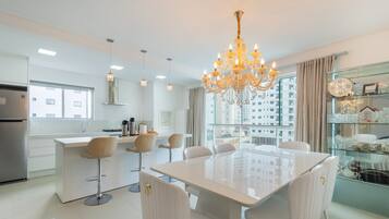 A modern kitchen with a central island, bar stools, and a chandelier.