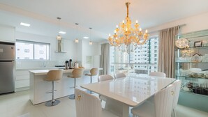 A modern kitchen with a central island, bar stools, and a chandelier. - Apto 3 quartos alto padrão em BC - GTR0301 (Balneário Camboriú)