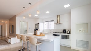 A modern kitchen with a central island, bar stools, stainless steel appliances, and pendant lighting. - Apto 3 quartos alto padrão em BC - GTR0301 (Balneário Camboriú)
