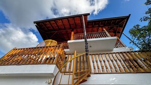 A multi-story building with a wooden balcony railing, a spiral staircase, and a red roof.