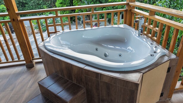 A hot tub on a wooden deck with steps leading up to it.