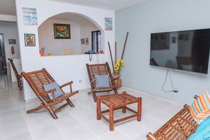 A living room with two wooden rocking chairs, a small table, and a TV mounted on the wall.