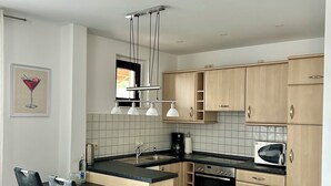 Une cuisine moderne dotée d’un îlot central, d’appareils électroménagers intégrés et d’un coin repas avec des chaises.