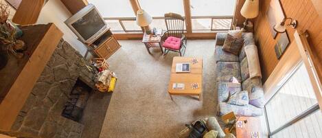 A cozy living room with a stone fireplace, a television, and comfortable seating.