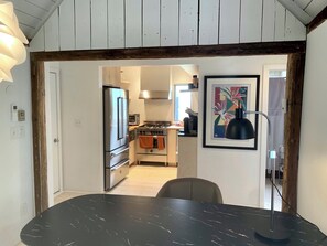 A modern kitchen with stainless steel appliances, a wooden ceiling, and a dining area with a marble table.