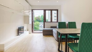 A modern apartment with a dining area, a sofa, and a balcony with a view of buildings and trees. - Spectacular flat in the heart of Shoreditch (London)