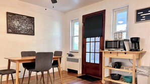 A room with a wooden dining table and chairs, a microwave, coffee maker, and a shelf with kitchenware. - Charming 2-bedroom on the West Side! Pet-friendly and quiet! (Cincinnati)