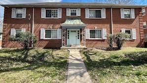 A two-story brick building with a central entrance, a small porch, and a green roof. - Charming 2-bedroom on the West Side! Pet-friendly and quiet! (Cincinnati)
