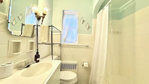 A bathroom with a sink, toilet, and shower. There is a mirror, a towel rack, and a window with curtains. - Charming 2-bedroom on the West Side! Pet-friendly and quiet! (Cincinnati)