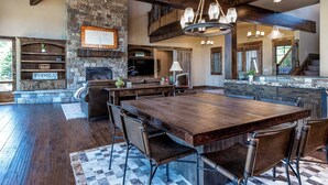 A spacious kitchen with a large island, stone fireplace, and wooden beams. - ON CALDERA SPRINGS GOLF COURSE--Spacious 6-bedroom house in enchanting SunRiver! (Bend)