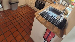 A compact kitchen with white cabinets, a microwave, a dishwasher, and a sink with a dish rack.