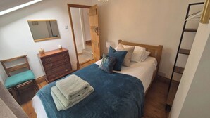 A bedroom with a bed, wooden dresser, and a mirror.