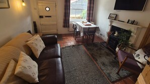 A cozy living room with a leather sofa, a dining table, and a fireplace.
