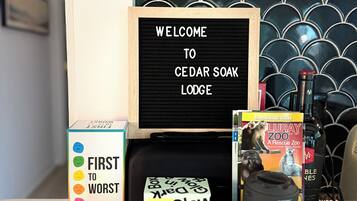 A welcome sign, a guestbook, a game box, and a book on a table with a patterned wall in the background.