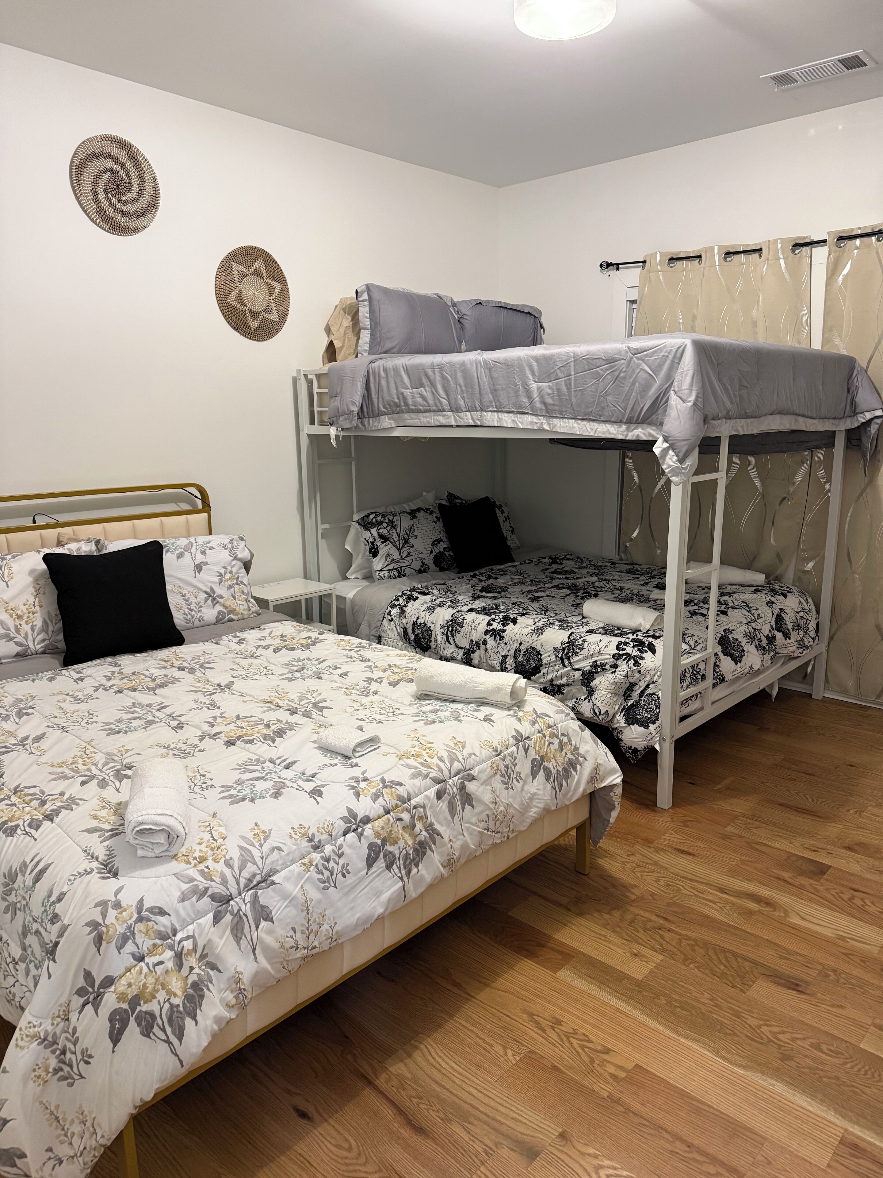 A dormitory room with two bunk beds, a single bed, and a wooden floor.