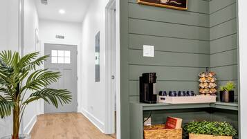 A hallway with a coffee bar sign, wooden flooring, and a potted plant.