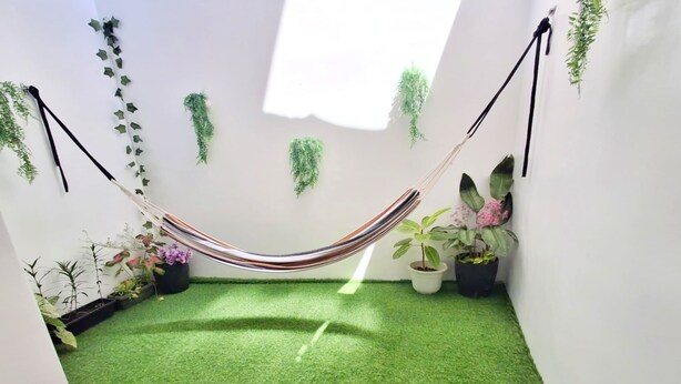 Una habitación con una hamaca, césped artificial y plantas en macetas.