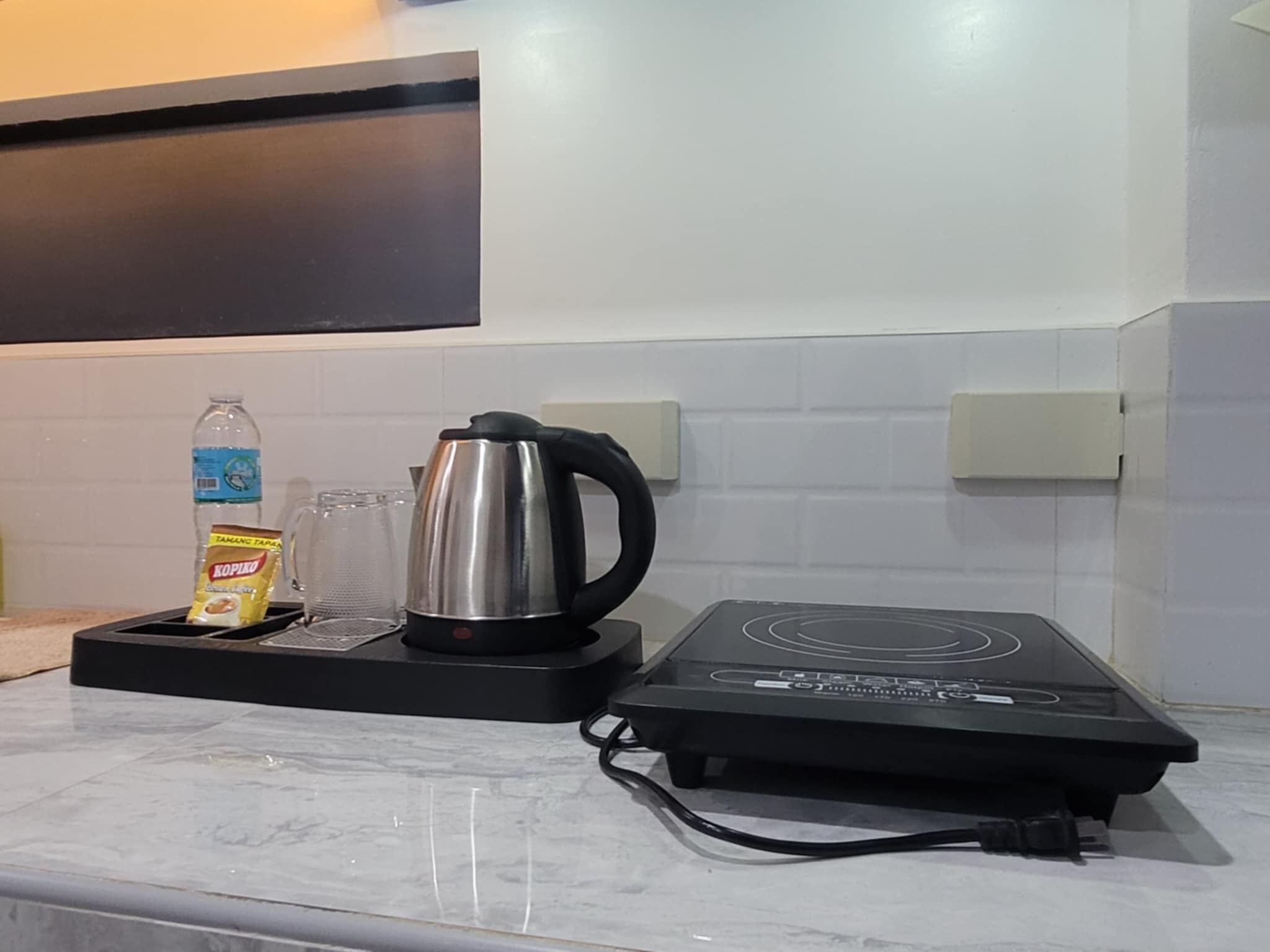 A kitchen counter with a kettle, a bottle of water, and a packet of Kopi Luwak coffee.