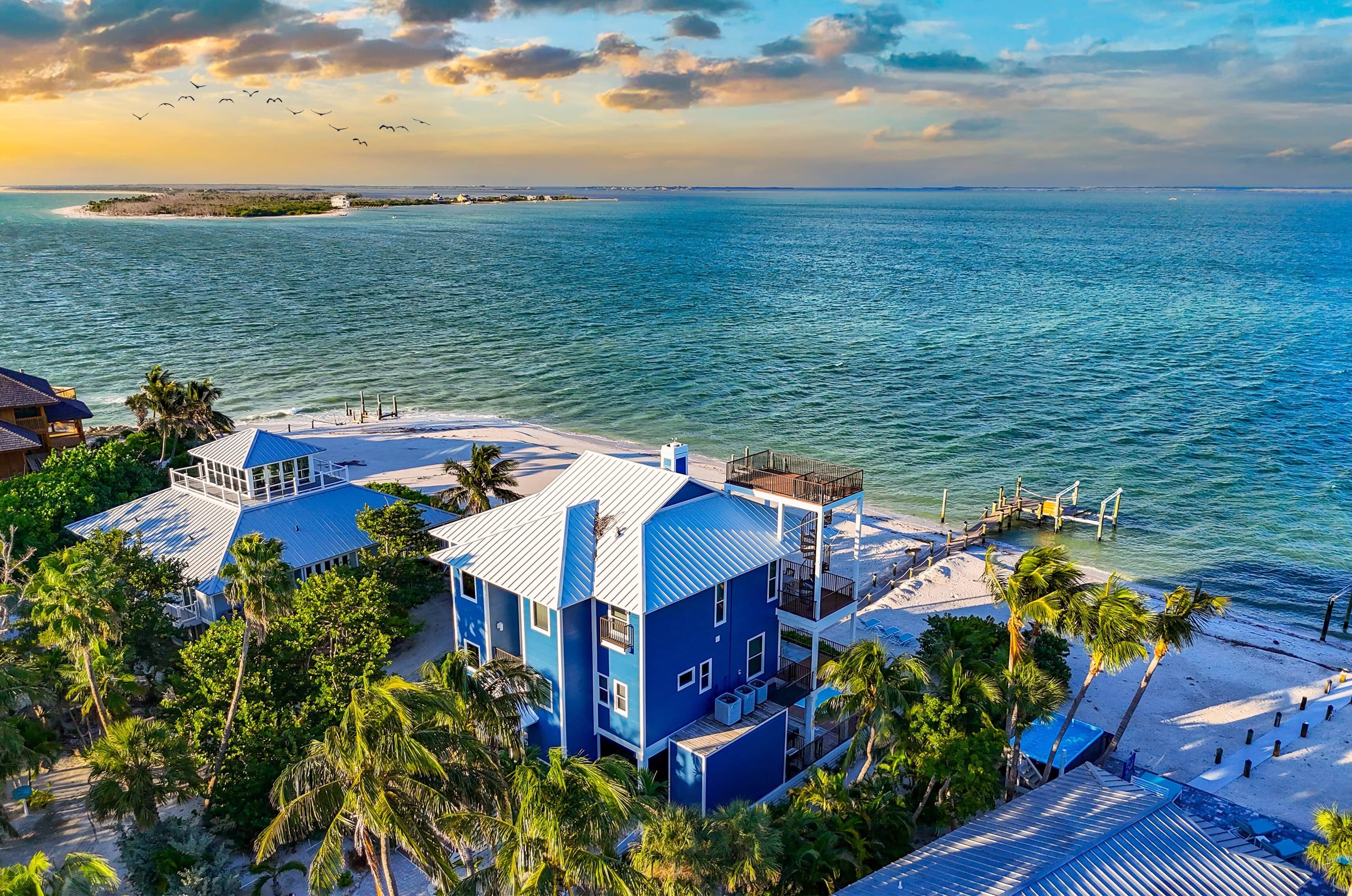 A coastal property with a large house, a beach, and a pier.