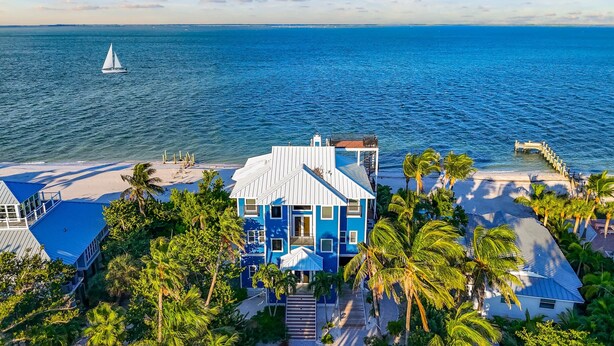 A beachfront property with a large house, a pier, and a sailboat on the water. - Gran Palacio-Beachfroont,Pool, Fishing & 360 Views, North Captiva Luxury Escape (Lee County)