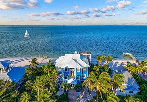 A beachfront property with a large house, a pier, and a sailboat on the water. - Gran Palacio-Beachfroont,Pool, Fishing & 360 Views, North Captiva Luxury Escape (Lee County)