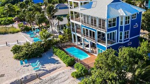 A multi-story building with a pool, surrounded by palm trees and beach chairs. - Gran Palacio-Beachfroont,Pool, Fishing & 360 Views, North Captiva Luxury Escape (Lee County)